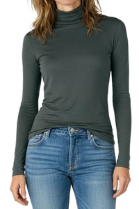 Woman wearing a green turtleneck t-shirt and blue jeans on a white background