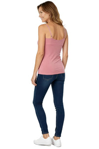 Woman wearing silky rose pink camisole top with adjustable straps and dark blue skinny jeans