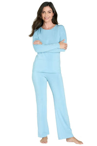 Woman wearing light blue fold-down lounge pants and matching long-sleeve top barefoot on white background