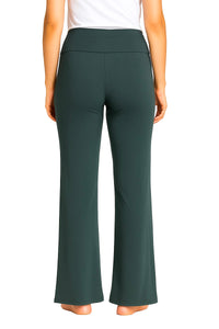 Back view of woman wearing dark green flare pants and white top, barefoot on white background