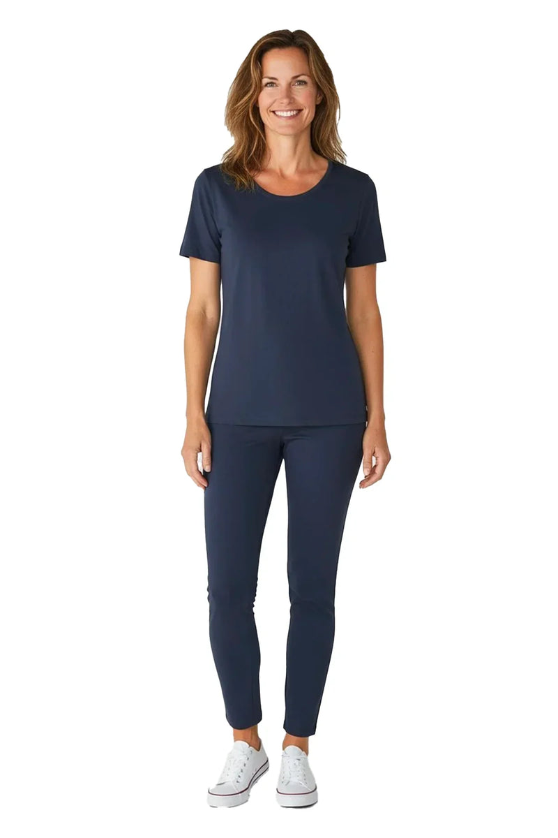 Smiling woman wearing steel blue short sleeve top and matching pants with white sneakers on white background