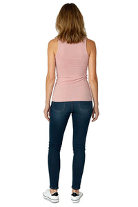 Woman wearing a light pink tank top, dark skinny jeans, and white sneakers, viewed from behind