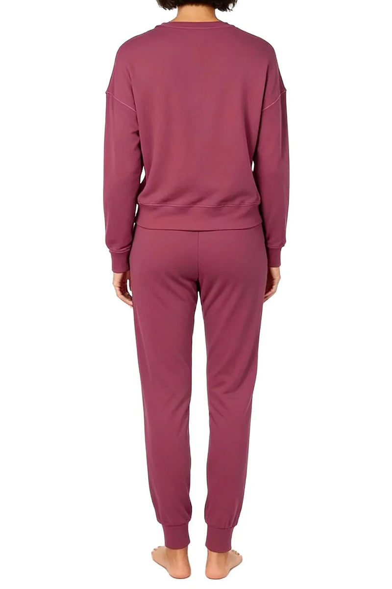 Woman wearing rosewood pink long sleeve top and jogger pants viewed from back on white background