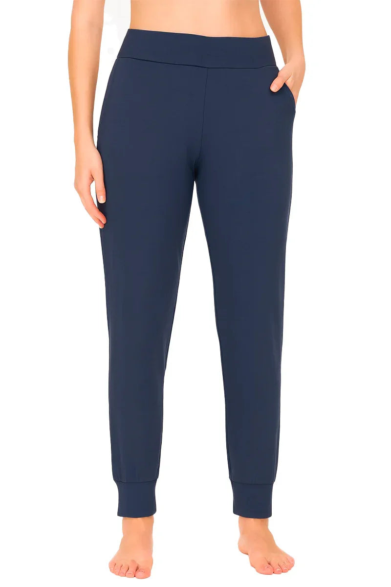 Woman wearing steel blue jogger pants with cuffed ankles and hands in pockets