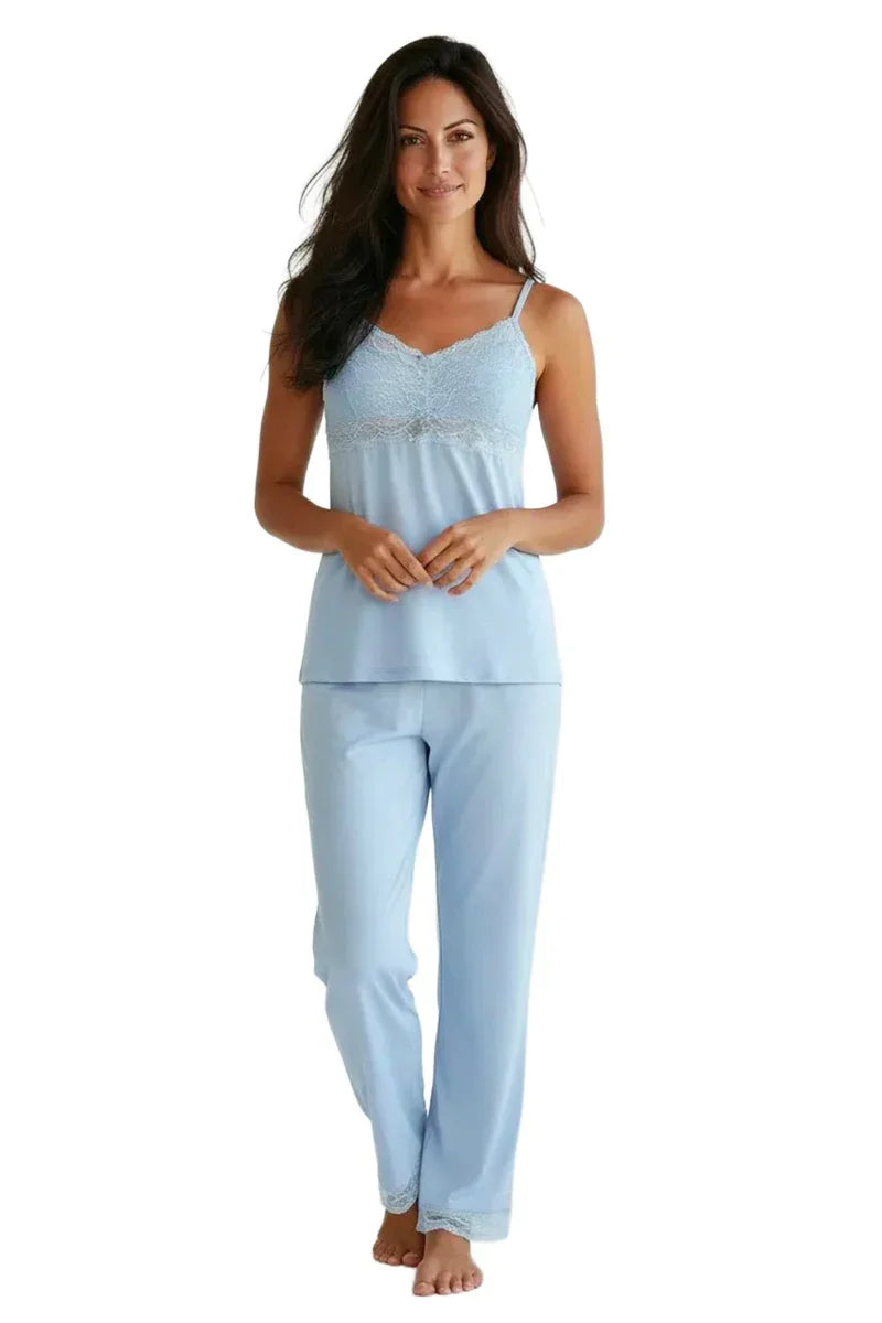Woman wearing light blue lace-trimmed camisole and matching pajama pants on white background