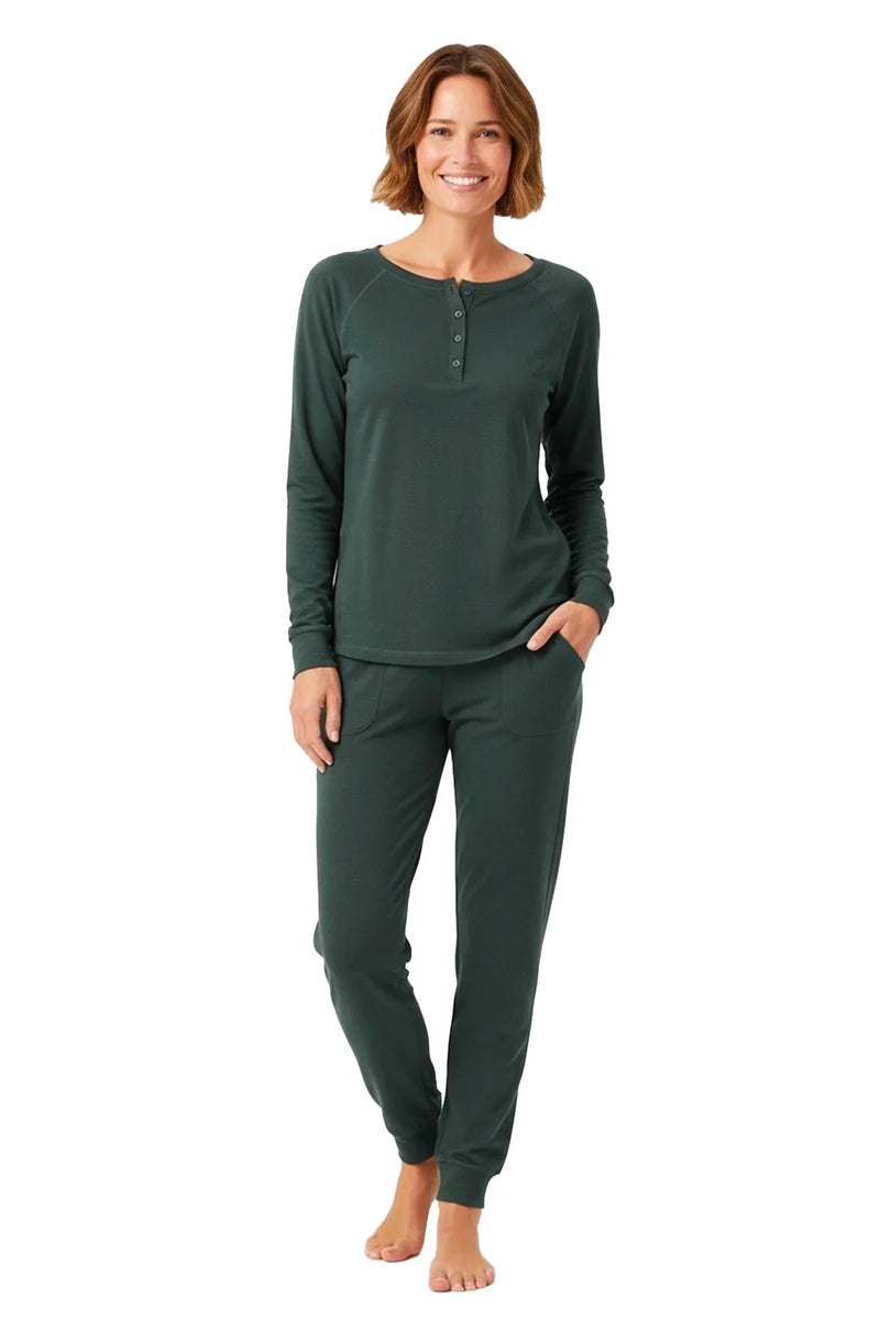 Smiling woman wearing dark green long-sleeve top and matching jogger pants lounge set barefoot