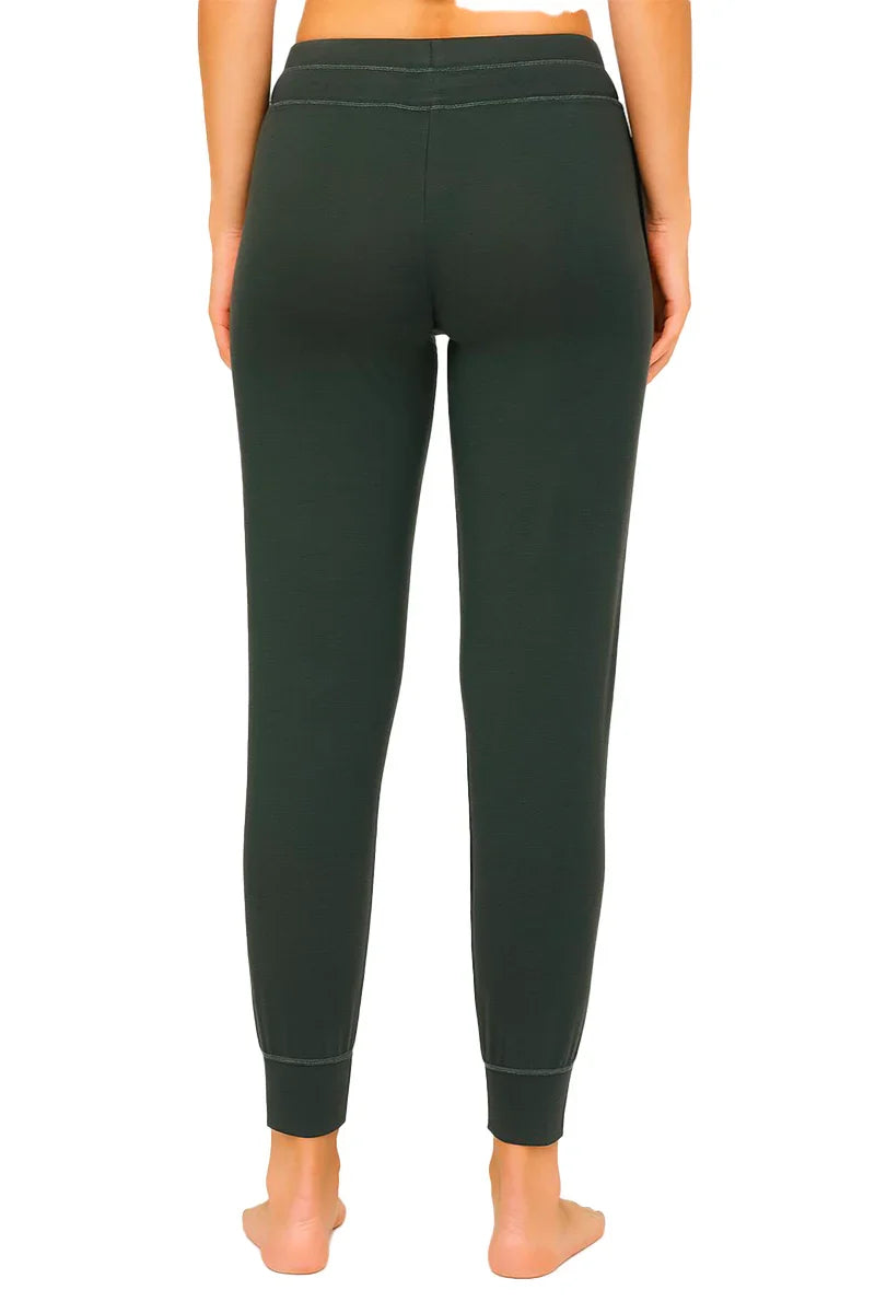Back view of woman wearing dark green fitted jogger pants with cuffed ankles on white background