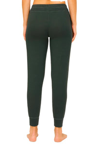 Back view of woman wearing dark green fitted jogger pants with cuffed ankles on white background