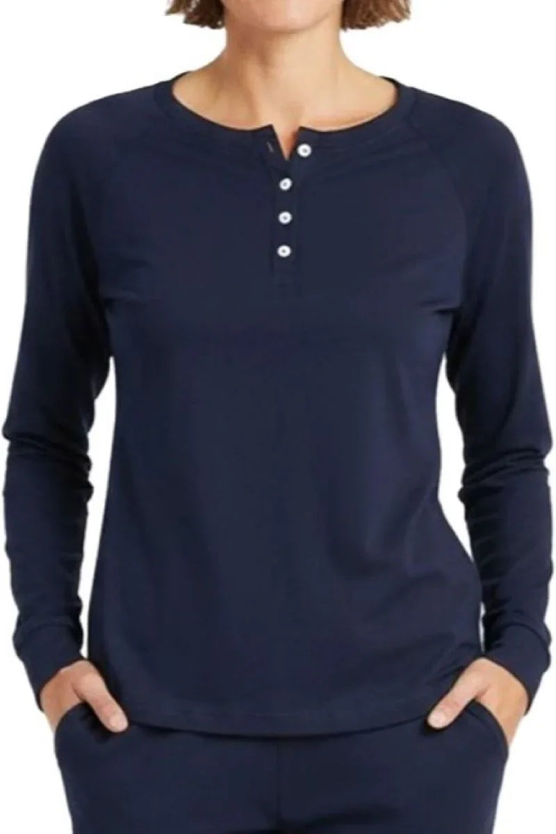 Woman wearing a midnight blue long-sleeve henley shirt with four white buttons, hands in pockets