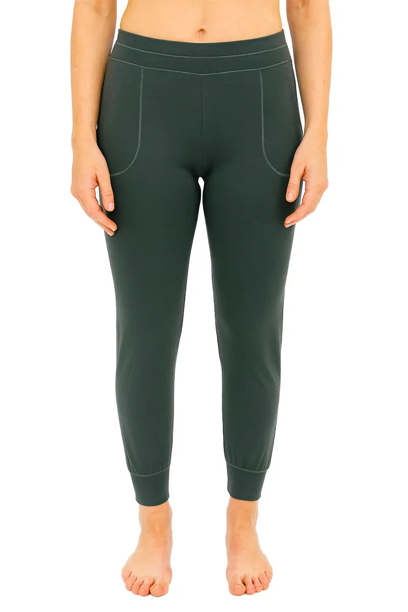 Front view of woman wearing spruce green jogger pants with pockets and fitted cuffs, barefoot